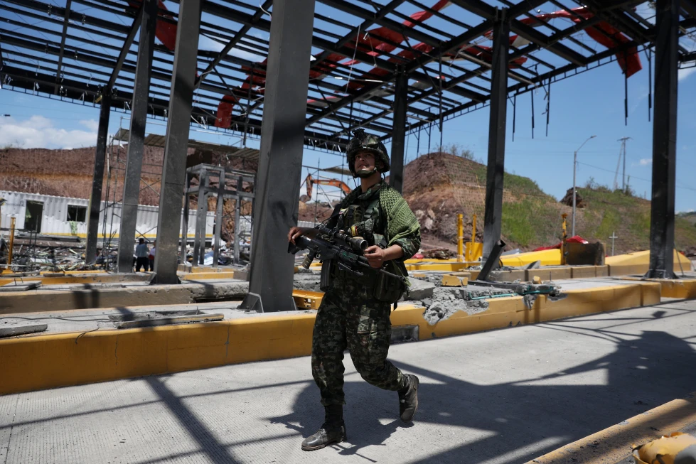 En la foto, Un soldado camina por una estación de peaje de la Carretera Panamericana, dañada por la explosión de un coche bomba que el ejército atribuyó a grupos disidentes de las FARC, el sábado 8 de agosto de 2026, en Santander de Quilichao, Colombia.