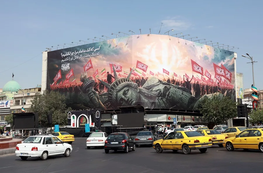 En la foto, Vehículos pasan junto a una valla publicitaria antiestadounidense en la plaza Enghelab, en el centro de Teherán, en una fotografía de archivo