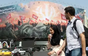 En la foto, Estudiantes iraníes pasan junto a un cartel contra Estados Unidos, hoy en Teherán