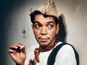 Retrato en color de Cantinflas con sombrero y pañuelo, conservando el grano de la fotografía original.