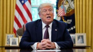 Donald Trump sentado frente a las banderas de Estados Unidos en una oficina