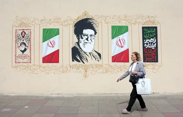 En la foto, Una mujer camina junto a un mural del difunto líder supremo iraní, el ayatolá Ali Jamenei, en Teherán
