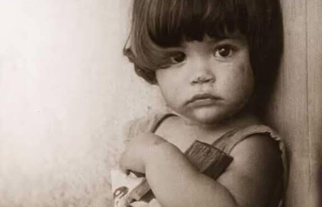 En la foto, una niña sujeta un trozo de malo como si fuera una muñeca