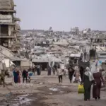 En la foto, Residentes palestinos caminaban entre las ruinas de edificios residenciales destruidos en el barrio de Al-Sheikh Radwan, en la ciudad de Gaza
