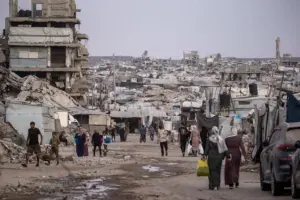 En la foto, Residentes palestinos caminaban entre las ruinas de edificios residenciales destruidos en el barrio de Al-Sheikh Radwan, en la ciudad de Gaza