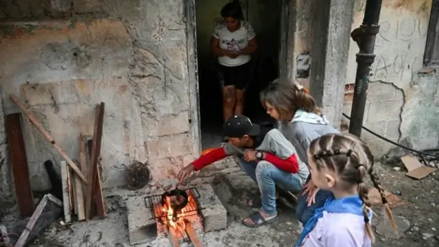 En la fot, un padre cubano cocina con leña por la falta de combustible y electricidad