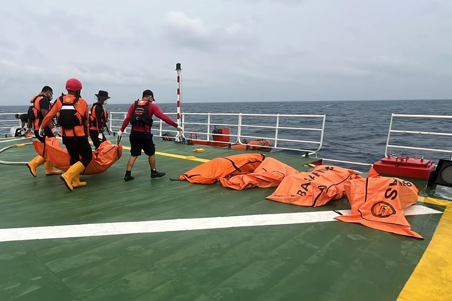 En la foto, rescatistas trasladan el cuerpo de una víctima del naufragio de un transbordador enn un barco de la agencia, en el mar de Java, Indonesia