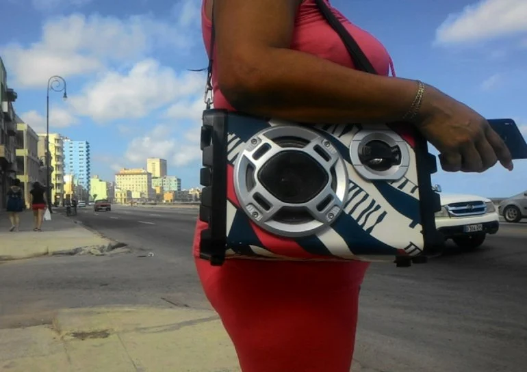 En la foto, una mujer escucha música alta al lado del malecón