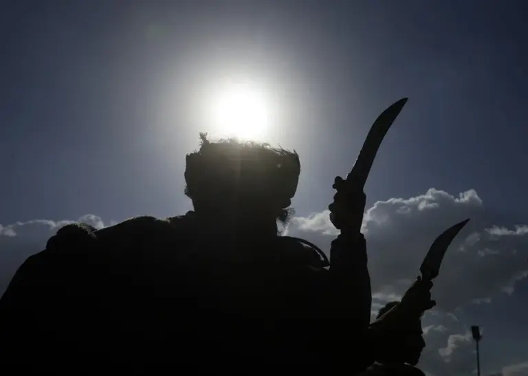 En la foto, Personas realizan una danza con dagas mientras sus siluetas se recortan contra el cielo en una calle de Saná, Yemen