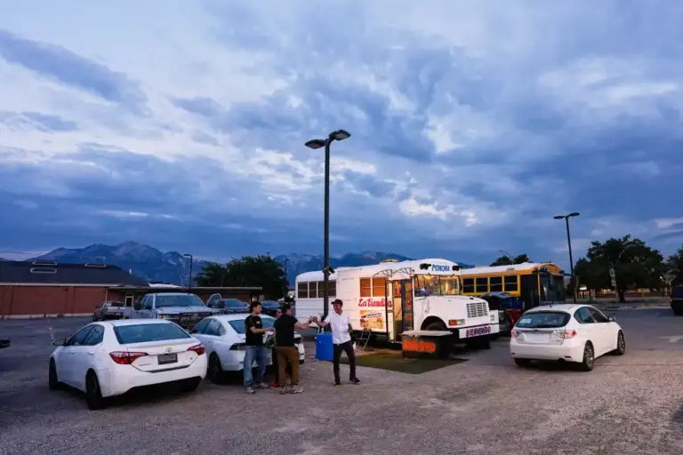 En la foto, El venezolano Jadiel Rodríguez saluda a la gente frente a su autobús escolar convertido en tienda, donde vende productos venezolanos, el martes 14 de julio de 2026 en Midvale, Utah