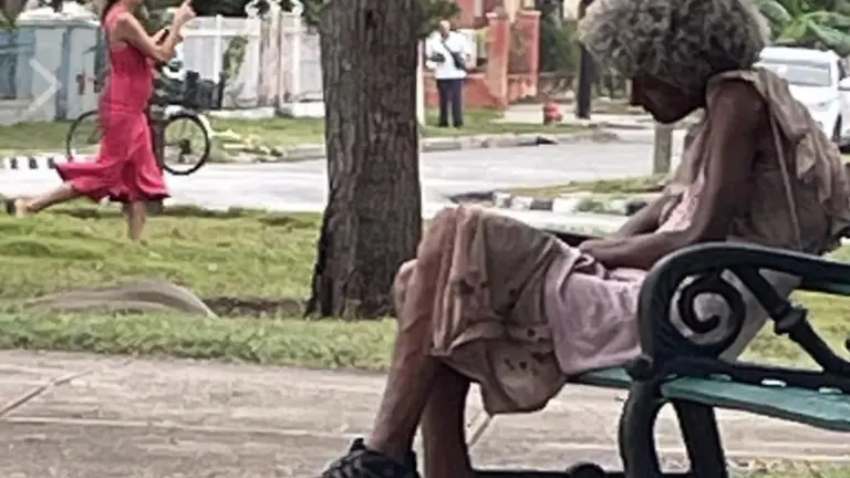 En la foto, una mujer pobre dormita de día en un parque de Cuba