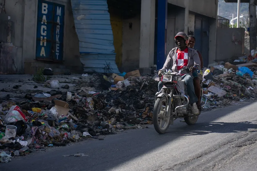En la foto, Al menos 164 personas asesinadas en masacres en julio y agosto en Haití, según una ONG local 6 En la foto, personas movilizándose en una motocicleta por una calle cubierta de basura, en Puerto Príncipe (Haití)