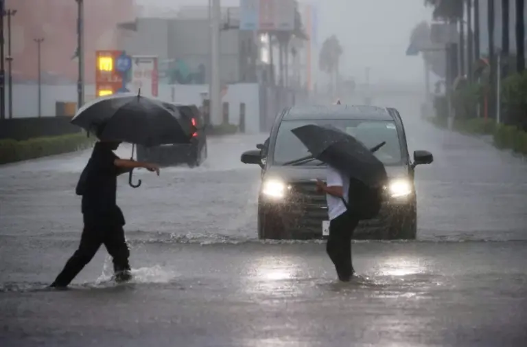 En la foto, Dos personas tratan de cruzar una calle inundada en Funabashi, prefectura de Chiba, cerca de Tokio