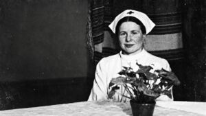Irena Sendler con uniforme de enfermera y un ramo de flores en una fotografía histórica en blanco y negro
