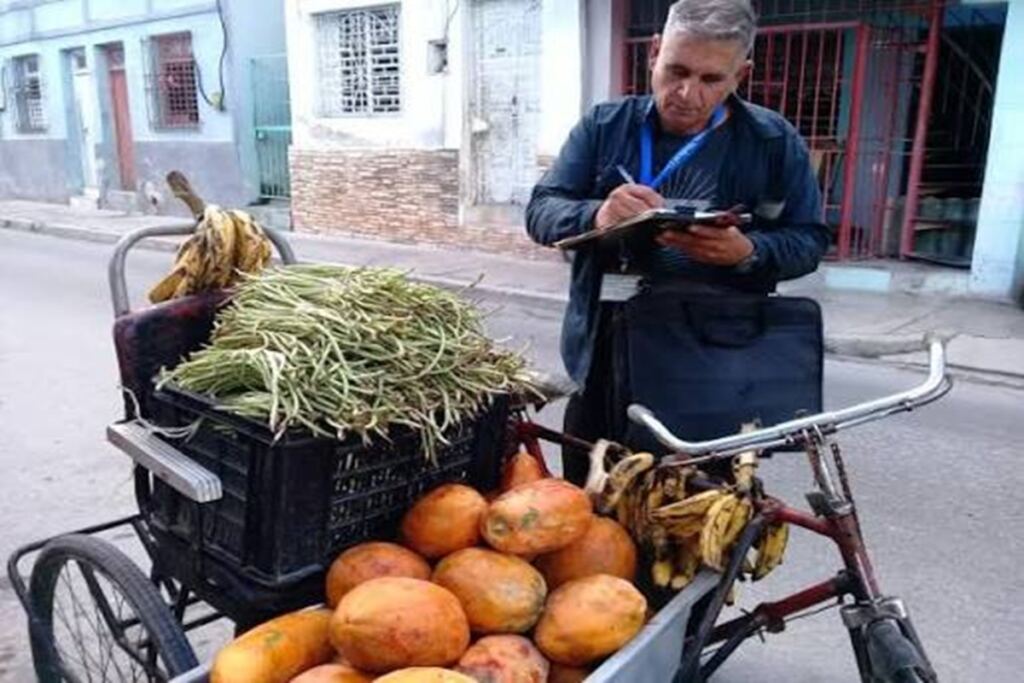 En la foto, un inspector multa a un hombre que vende habichuelas, frutabomba y plátanos