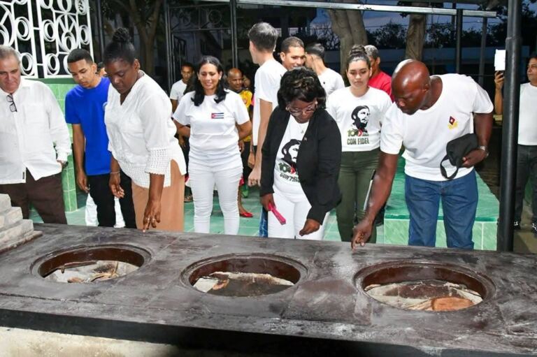 En la foto, la secretaria del Partido Comunista en Santiago de Cuba y otros chicharrones del castrismo tocan la 'moderna' cocina de leña para dejar claro que es de verdad, que es un logro de la revolución