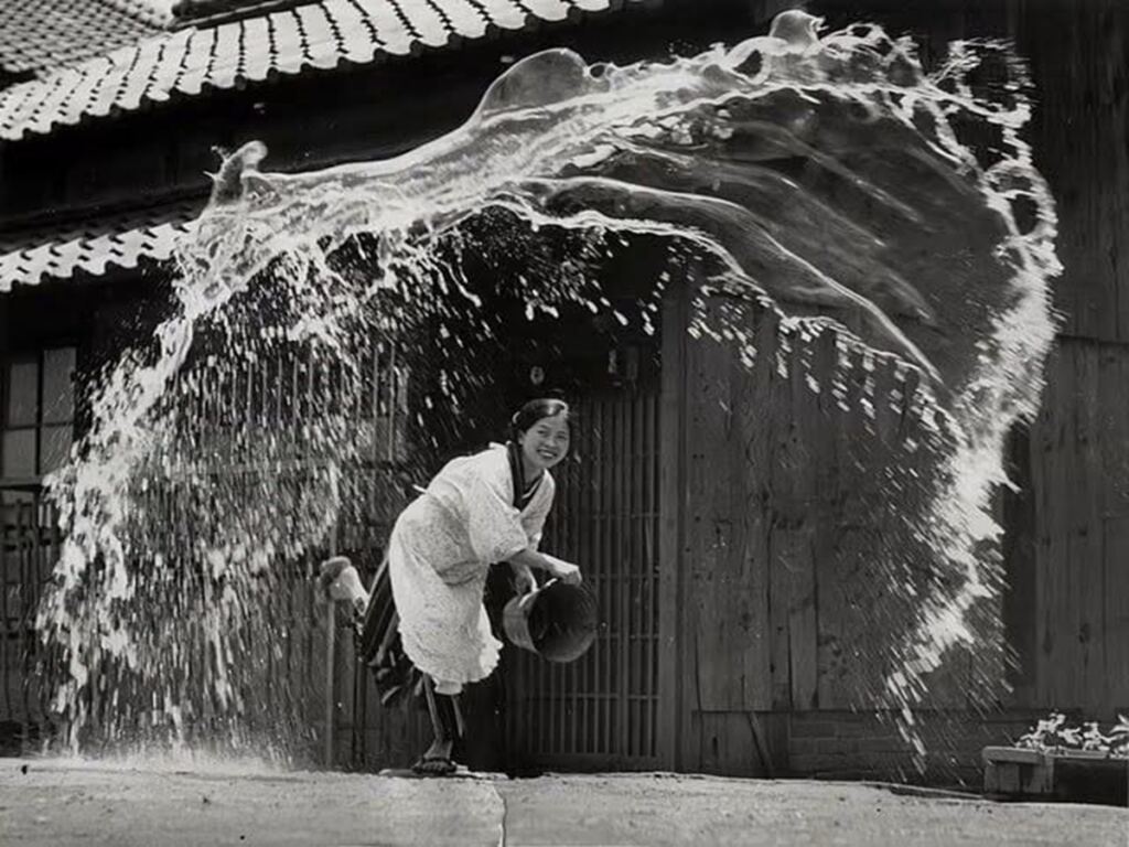 En la foto, una mujer japonés lanza agua a la calle