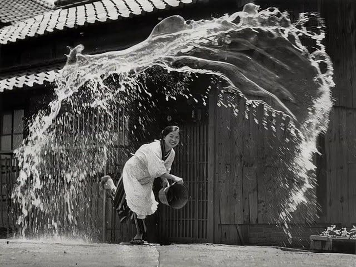 En la foto, una mujer japonés lanza agua a la calle
