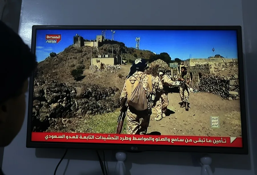 En la foto, Una persona observa una transmisión televisiva que muestra a combatientes hutíes en Saná (Yemen)