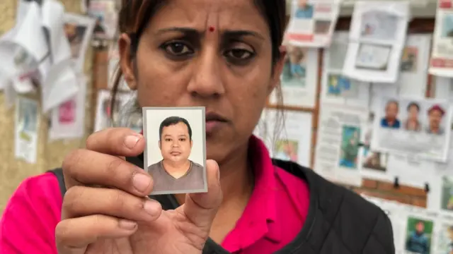 En la foto, Usha Khatri muestra una foto de su esposo, Indra Bahadur, desaparecido desde las inundaciones del mes pasado en el exterior del hospital universitario Tribhuvan, en Katmandú