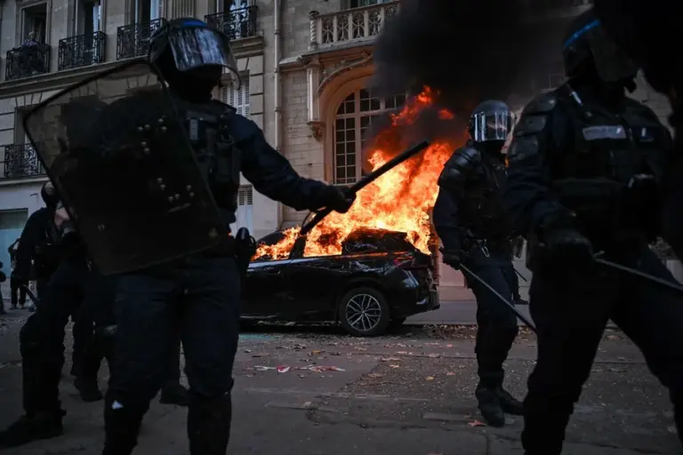 En la foto, Un automóvil arde mientras se producen enfrentamientos con la policía antidisturbios
