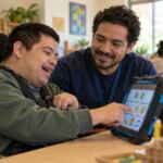 Adulto usando comunicación aumentativa con apoyo de un terapeuta en un centro comunitario